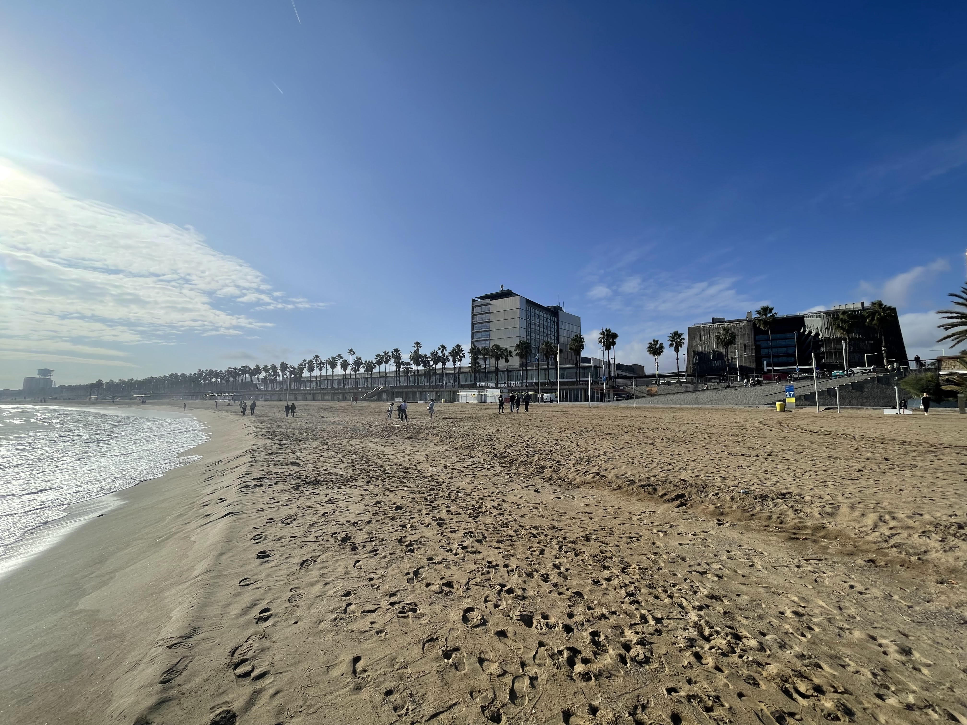 Barceloneta beach with the biomedical research park's dark cantilevered building on the shoreline